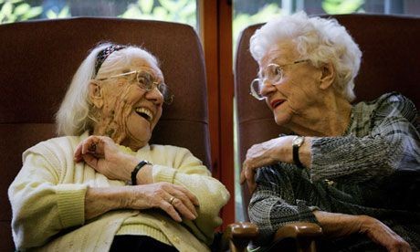 This is a photo of two women in a long term care community laughing and discussing dementia friendly books and reminiscing. NANA’S BOOKS are award-winning large print books and beloved dementia reading materials.