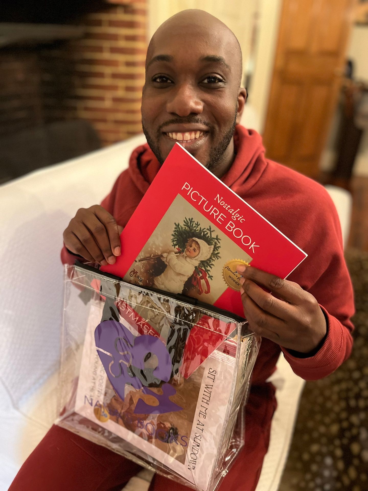  A young male caregiver holds a tote full of NANA’S BOOKS. He is wearing a red sweatshirt. NANA’S BOOKS are for people living with dementia.